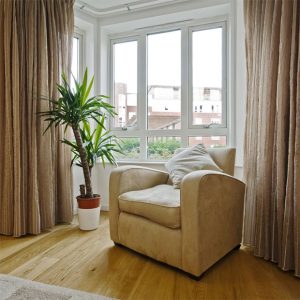 Single sofa next to a plant in front of a White Aluminium Window
